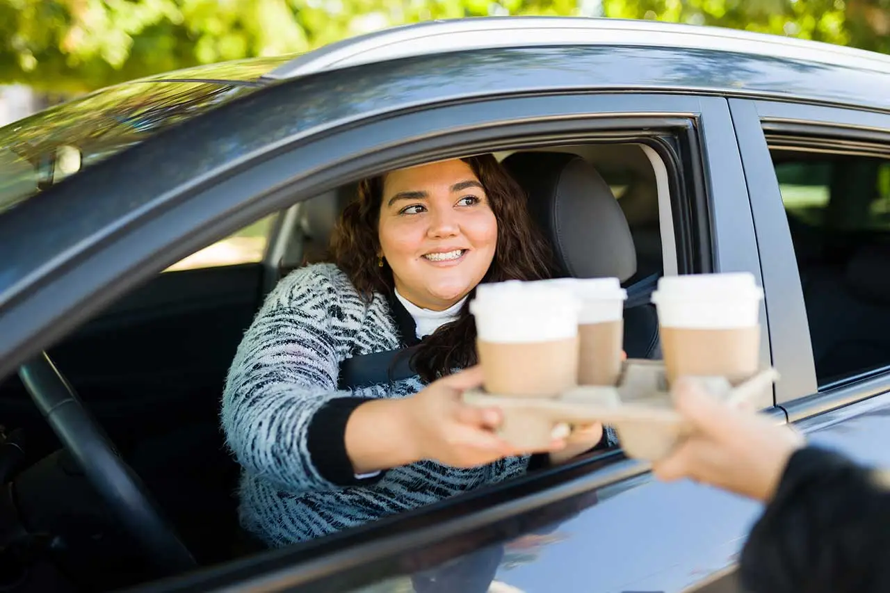 Happy big woman buying coffee in the drive thru Happy big woman buying coffee in the drive thru